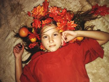 High angle view of girl with red leaves and fruits on bed