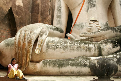 Woman sitting against buddha statue in temple