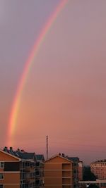 Rainbow over city against sky