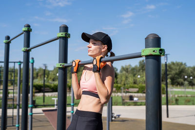 Woman standing by railing against sky