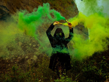 Man holding distress flare while standing in forest