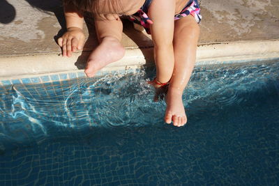 Low section of baby sitting at poolside