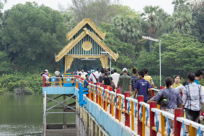 Rear view of people walking on bridge over lake