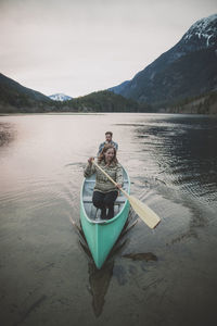 High angle view of young couple canoeing on lake against clear sky