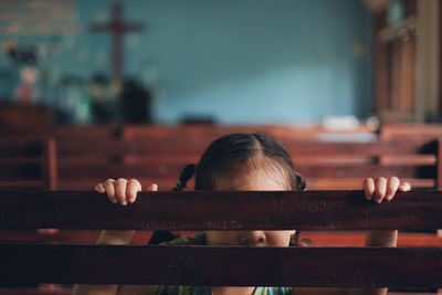 Girl hiding behind pew in church