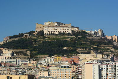 Buildings in city against clear blue sky