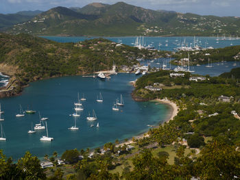 High angle view of sailboats moored on sea by mountains