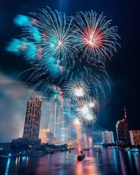 Firework display over illuminated buildings in city at night