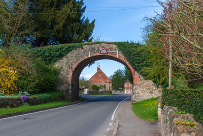 Road seen through arch bridge against clear sky