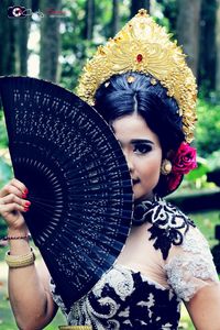 Close-up portrait of young woman in traditional clothing holding paper fan
