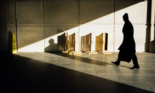 Shadow of woman walking on tiled floor in building