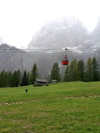 Overhead cable car over mountains against sky during winter