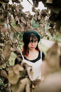 Portrait of young woman standing against plants