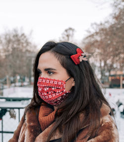 Portrait of beautiful woman wearing winter clothes and red face mask with christmas pattern