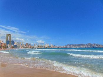 Scenic view of sea by buildings against blue sky