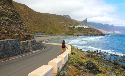 Man on road by sea against sky