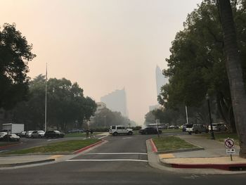 Cars on street in city against sky