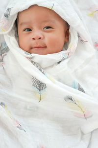 A cute 3 month asian baby smiling and happy with swaddled.