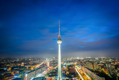 Aerial view of illuminated buildings against blue sky