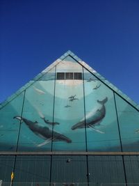 Low angle view of fish swimming in sea against clear blue sky