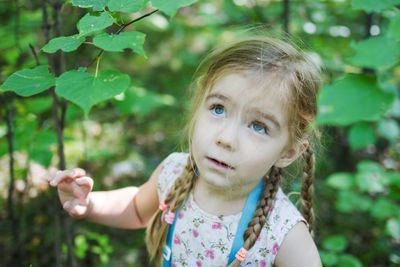 Portrait of young woman standing against trees