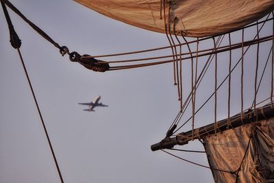 Low angle view of ship and airplane against sky on sunny day