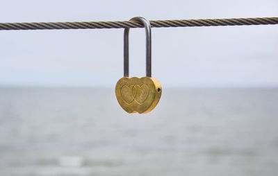 Close-up of padlocks on rope against sea