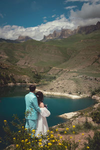 Bride and groom dressed elegant in their wedding gowns holding hands and hugging posing for their