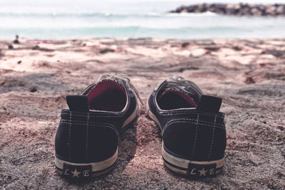 Close-up of shoes on beach