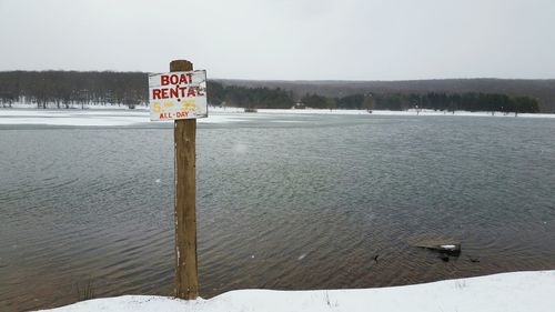 Signboard in lake during winter