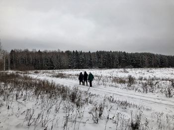 People walking on snow field against sky