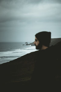 Side view of man on beach against sky