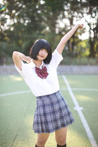 Young woman looking away while standing on field