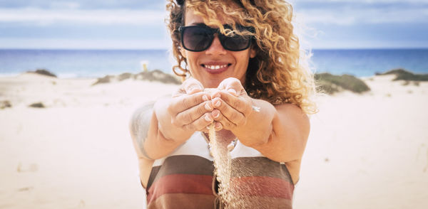 Low section of woman wearing sunglasses at beach