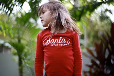 Cute girl looking away against trees