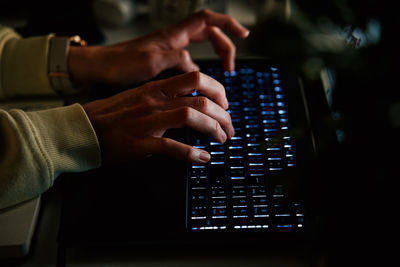 Anonymous woman working on laptop at night