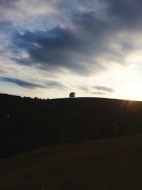 Scenic view of silhouette field against sky during sunset