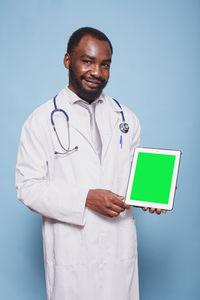 Portrait of doctor standing against blue background