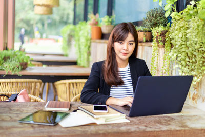 Portrait of woman using phone while sitting on table