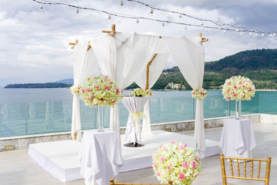 Flowers hanging on table by sea against sky