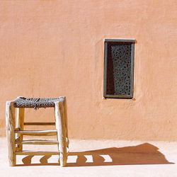 Chair against wall during sunny day