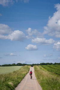 Rear view of person riding bicycle on road