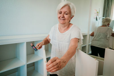 Smiling woman standing against wall at home