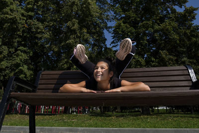 Girl in sportswear on a sunny summer day on the embankment in the park doing fitness and stretching