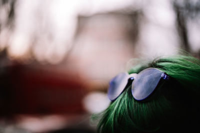 Close up of purple sunglasses on green haired head