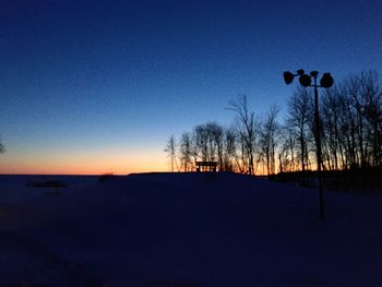 Silhouette trees on landscape against clear sky during sunset