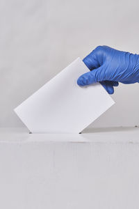 Close-up of hand holding paper over white background