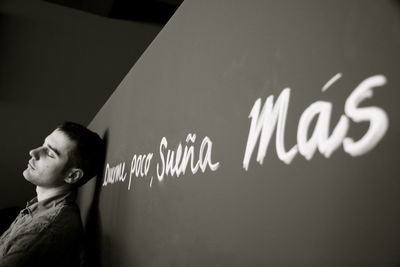 Man with eyes closed standing by wall