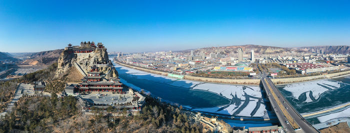 High angle view of city buildings against blue sky