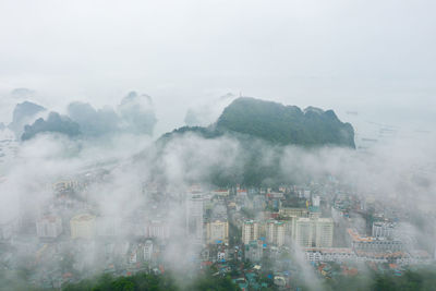 Aerial view of cityscape and rock formations during foggy weather
